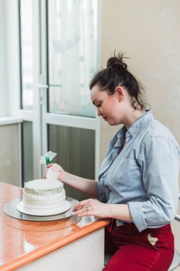 pudra kek üzerine krema sıkar. Kız bir kek yapmak