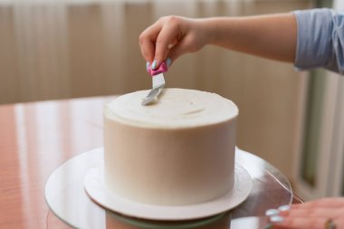 Pudra kek üzerine krema düzeyleri. Aşçı bir pasta oluşturur, topladığı ve krema ile kapsar ve bir spatula ve sıyırıcı ile düzeyleri.