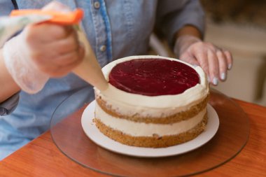 pudra kek üzerine krema sıkar. Kız bir kek yapmak