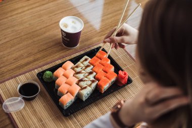 Kız yemek çubukları ile rulo belirledi ve kahve içiyor. California, Philadelphia