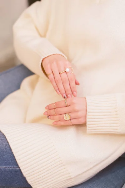 A lot of stylish rings on their hands. Girl holds hands on a sweater