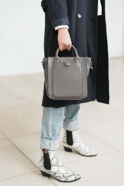 El çantası. elinde mavi-gri bir çantada bir kızın dikey fotoğraf ve Kazak Siyah ve beyaz botlar. mavi kot ve mavi yağmurluk