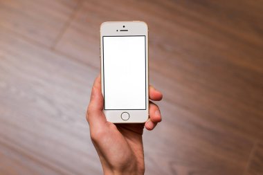 Samara, Rusya-05.04.2019: ahşap kahverengi arka planda izole iPhone SE 5S altın tutan adam el