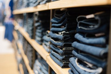 mağazada bir dükkan penceresinde kot yığını. Katlanmış kot rafta.