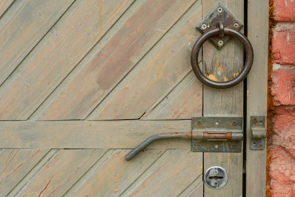 Old vintage door handle on a wooden door. The shutter is on the brown door. Round handle and open lock. Horizontal photo