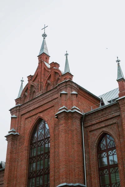 details of the catholic church. The church is of red brick, with crosses and thin windows.