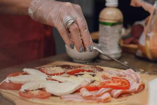 Una Mujer Con Guantes Desechables Espolvorea Pizza Queso Con Jamón — Foto de Stock