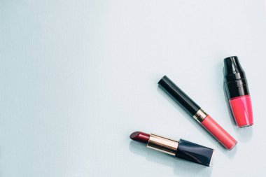 Ruj çeşitli, pastel mavi arka plan üzerinde parlak. Kırmızı, pembe, şeftali mat ruj vardır. Kadın kozmetik kavramı. Göz alıcı yaşam.