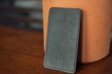 Ahşap arka planda erkeksi deri telefon kılıfı. Aksusekar yanında saksı çiçek