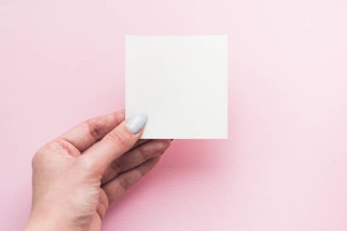 Kızın eli beyaz bir arka plan üzerinde boş beyaz bir kartpostal tutuyor. kopyalama alanı