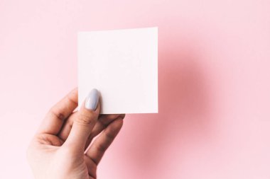Kızın eli beyaz bir arka plan üzerinde boş beyaz bir kartpostal tutuyor. kopyalama alanı