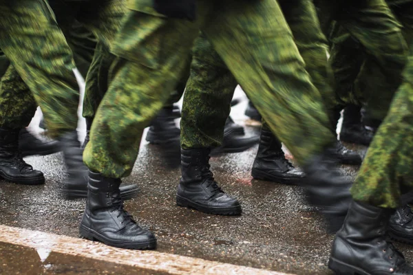 Soldier boots walking on wet asphalt during the parade of memory. The military marching down the street. Many shoes and camouflage clothing. Motion lubrication