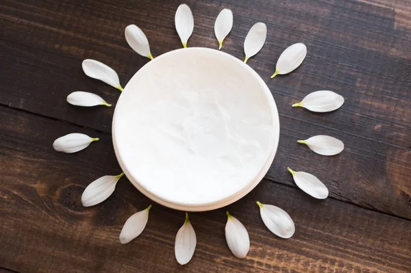 Skin care. The concept of solar skin care. White mask for the body and face on a wooden table in the video of the sun. Petals in the shape of the sun.