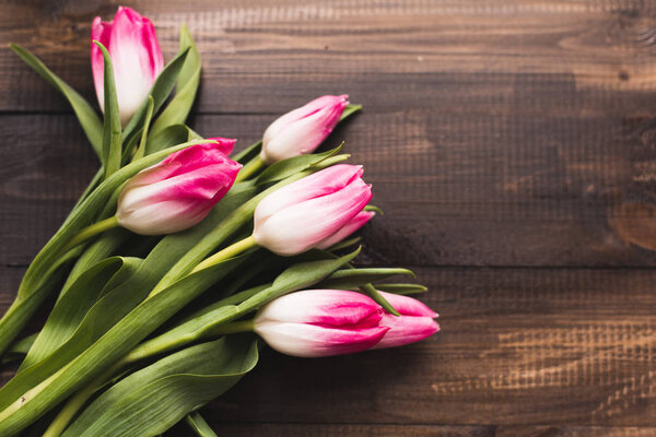 Fresh beautiful pink tulips on a wooden dark background with copy space