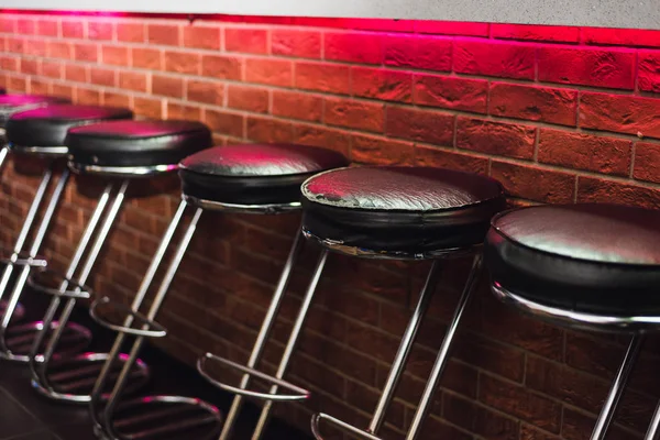 Bar stools at the counter in neon light. leather chairs at the bar in the nightclub — Stock Photo, Image