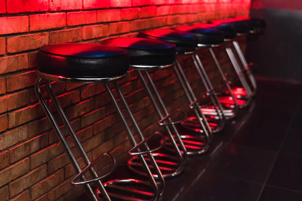 Bancos de bar no balcão em luz de néon. cadeiras de couro no bar na boate — Fotografia de Stock
