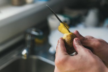 Adam evde lavaboda bir bıçakla patates temizler. küçük patates soyma. lavaboda temizlik.