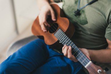 ukulele oyunu. Biraz gitar çalan bir adam. sanatçı evde ukulele müzik yazar.