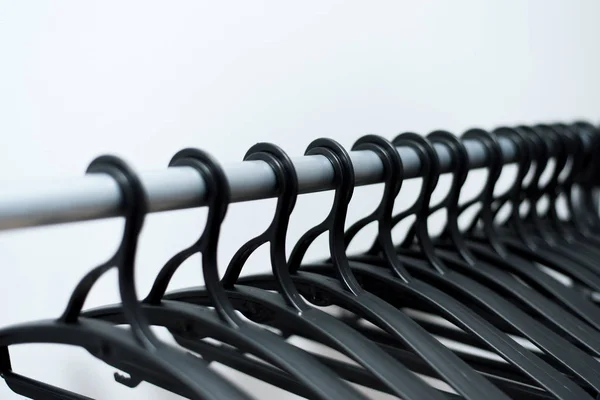 Black plastic hangers hang on a light background. many different hangers. — Stock Photo, Image
