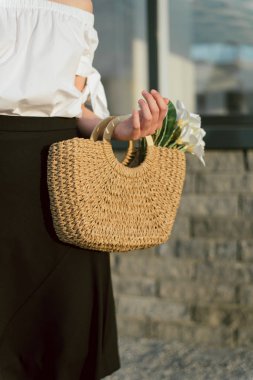 kız elinde hasır çanta. Kentsel manzara bir bej saman çantası ile kız. Beyaz çiçekler ile şık yaz çantası.