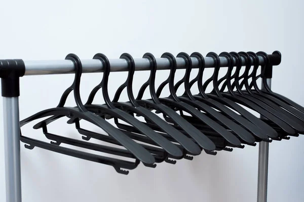 Zwarte kunststof Hangers hangen op een lichte achtergrond. veel verschillende Hangers. — Stockfoto
