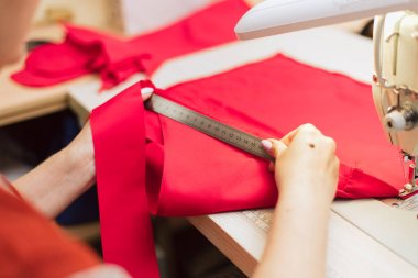 Terzi bir cetvel ile kumaş ölçer. Kadın bir konfeksiyon fabrikasında çalışıyor