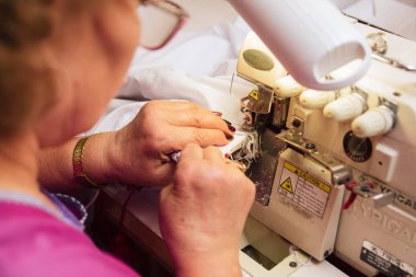 Yaşlı bir kadın dikiş makinesini diker. üretimde terzi nakışları.