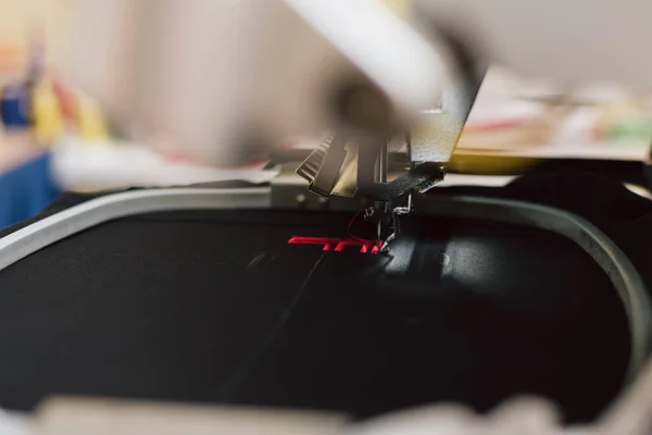 embroidering text on a sewing machine on an industrial scale. machine embroiders the letter f on the fabric.