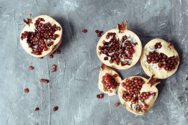 Gri bir grunge beton arka plan üzerinde birkaç olgun nar. Büyük kırmızı tanecikli el bombaları beton kaldırımda yatıyor.