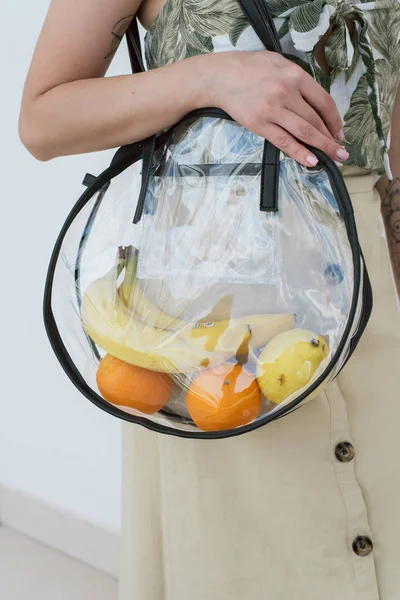 Plastic transparent shopping bag. Stylish reusable string bag with different fruits.