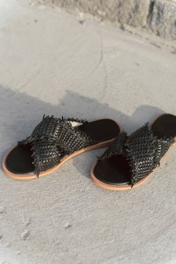 düz taban ile siyah hasır ayakkabı. Bacaklar olmadan şık yaz slates. Üzerinde bir gölge ile gri asfalt üzerinde moda kadın terlikler.