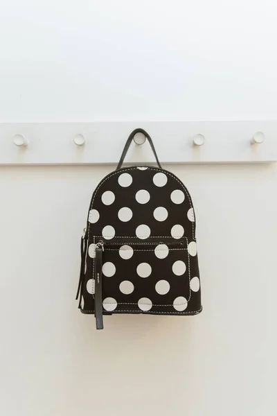 Schwarzer gepunkteter Rucksack. auf einem Kleiderbügel im Schrank. Ein Rucksack hängt an einem Haken in einer Umkleidekabine. — Stockfoto