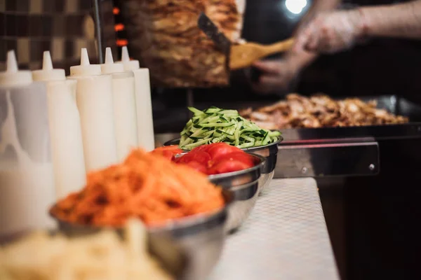 Bebidas con tomates, pepinos, zanahorias coreanas y papas fritas, platos de salsa en el fondo de kebabs y carne de pollo frito para shawarma . — Foto de Stock