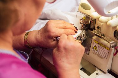 Yaşlı bir kadın dikiş makinesini diker. üretimde terzi nakışları.