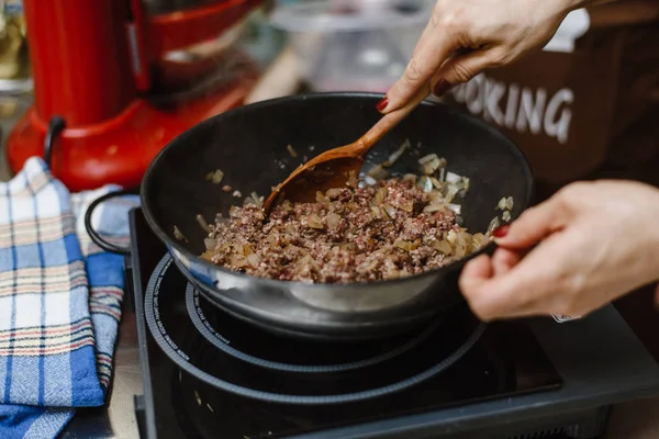 Кухар смажить фарш у глибокій сковороді. Готова начинка з цибулею в мисці на фоні спецій і зелені . — стокове фото