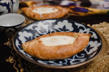 Doğu masasında Acara khachapuri. oryantal tabaklarda sıcak ekmek yumurta bir restoranda.