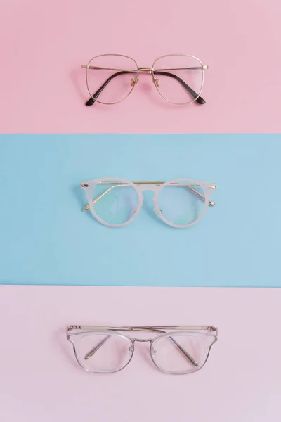 Pasztell háttérrel ellátott, stílusos képszemüveget. Három pár szemüveg lencsével egy rózsaszín és kék háttérrel. stílusos és trend optika — Stock Fotó
