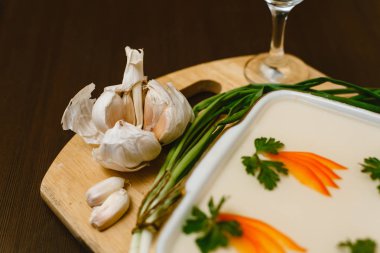 aspic, havuç, ahşap bir arka plan üzerinde maydanoz ile dekore edilmiştir. Kaçak içki, votka, sarımsak, yeşil soğan ve ekmek ile Rus-ulusal gıda