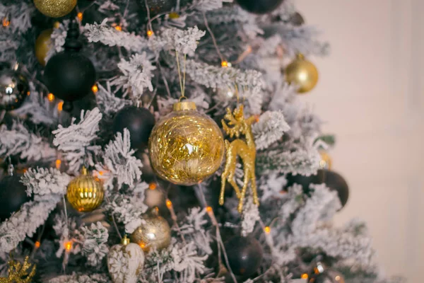 Albero di Natale verde scuro con neve artificiale bianca su di esso all'interno. Albero di Natale gotico con ornamenti in oro e blu scuro. Cervo d'oro e palline rotonde. Il concetto di Capodanno e Natale . — Foto Stock