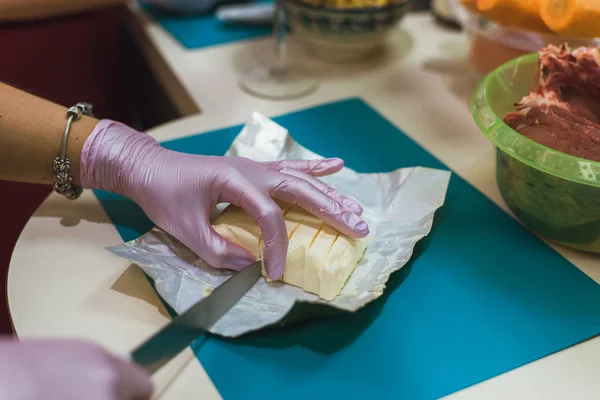 Женщина-повар в перчатках режет масло для приготовления пищи . — стоковое фото