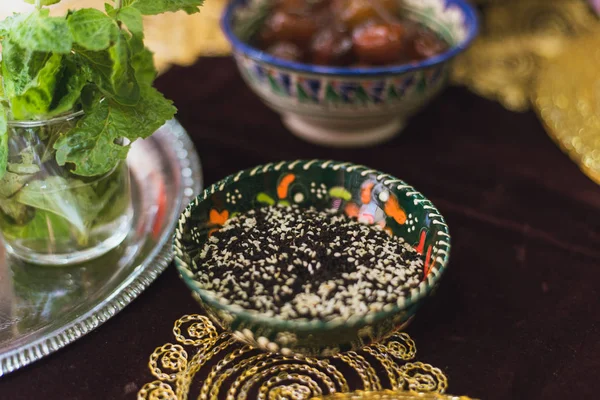 Black cumin in an oriental plate with patterns. White sesame and black cumin in the plate. Chernushka sowing. Oriental spices for cooking.