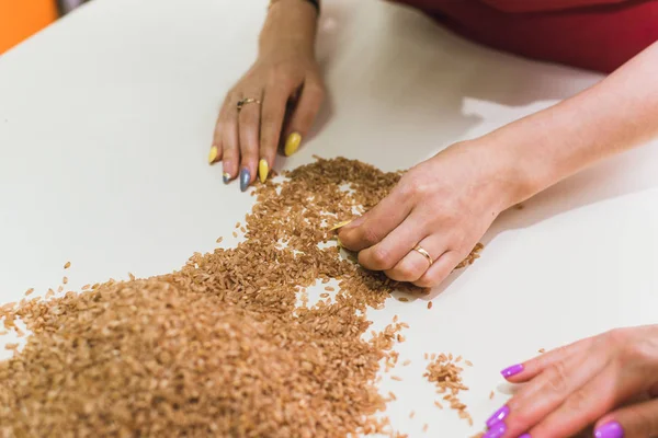 Девушки на кухне убирают рис из грязи. Очистка коричневого риса от шелухи — стоковое фото