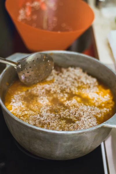 Cozinhar pilaf oriental na cozinha no caldeirão. Uma mulher prepara um prato de cordeiro, carne bovina, arroz, grão de bico, cenoura — Fotografia de Stock