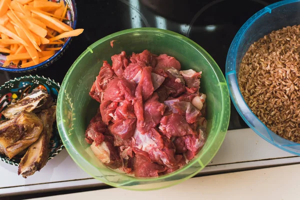 Carne crua, cenouras, arroz e bacon frito em copos de plástico. Preparação em pilau de cozinha na cozinha — Fotografia de Stock