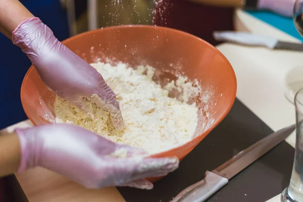 girl kneads dough made from flour and butter. A cook in gloves prevents flour from making dough
