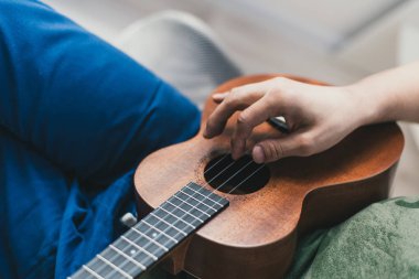 ukulele oyunu. Biraz gitar çalan bir adam. sanatçı evde ukulele müzik yazar