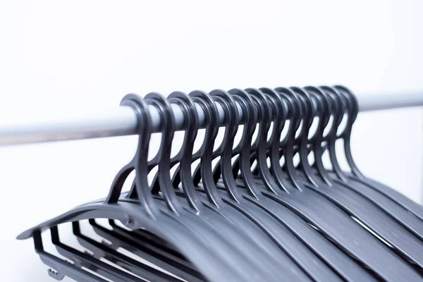 Zwarte kunststof Hangers hangen op een lichte achtergrond. veel verschillende hangers. vloercoat rack — Stockfoto