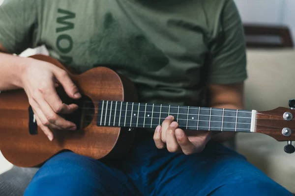 Ukulele game. a man playing a little guitar. the performer writes the music on the ukulele at home — Stock Photo, Image