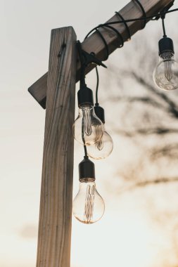 gün ışığında sokakta ampuller. Güneş açık havada öğleden sonra ahşap bir kaide üzerinde ampuller bir çelenk