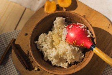tereyağı ile bir çömlek içinde pirinç lapası. Tahta kaşıkla Rustik tarzı. Ahşap bir masada süt lapası